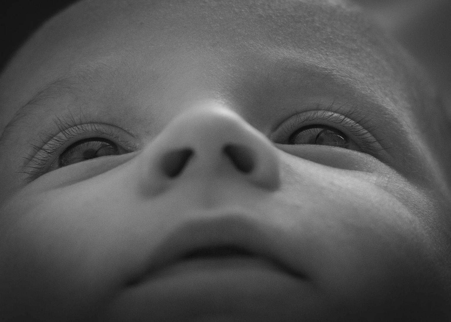 Gros plan en noir et blanc du regard et du visage d’un bébé.